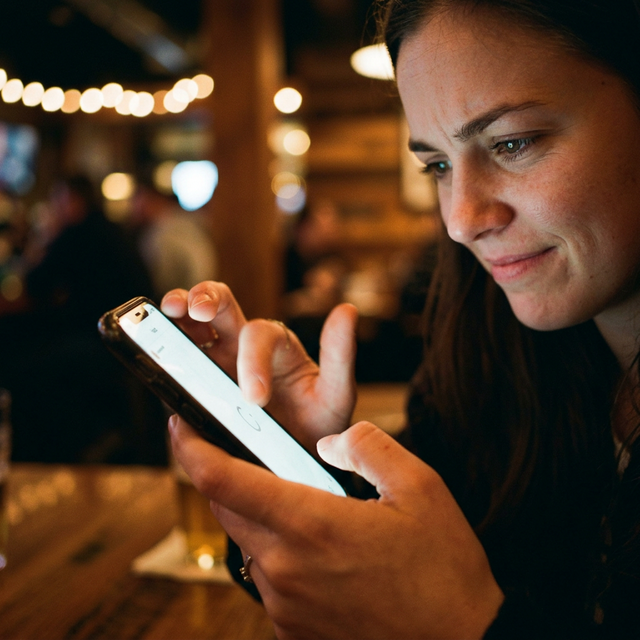 Woman looking at her phone with regret while sitting at a bar